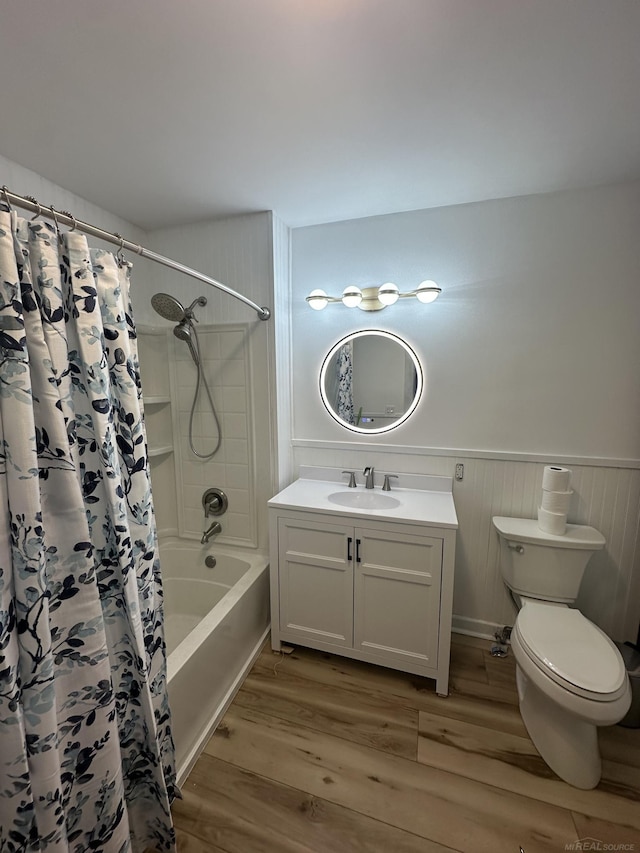 bathroom featuring toilet, wood finished floors, vanity, wainscoting, and shower / bath combination with curtain