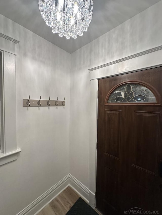 entryway with baseboards, a notable chandelier, and wood finished floors