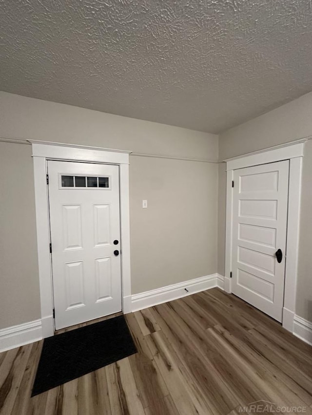 entryway featuring a textured ceiling, baseboards, and wood finished floors