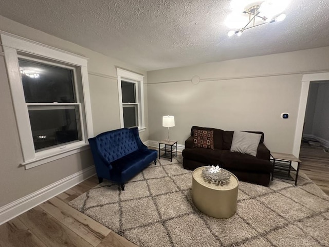 living area with a textured ceiling, baseboards, and wood finished floors