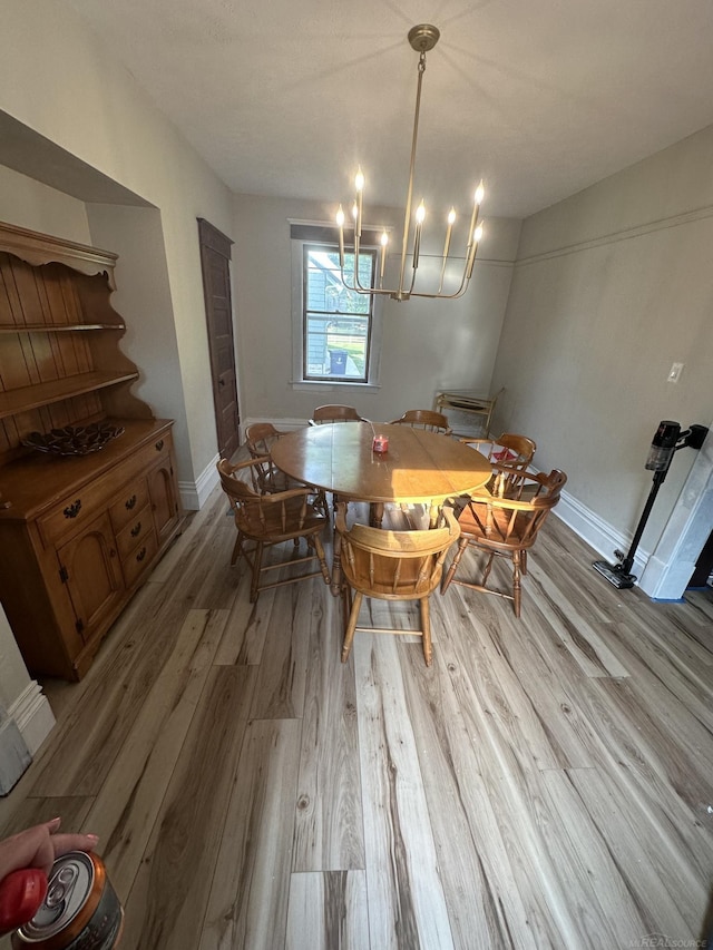 dining room featuring a chandelier, light wood-type flooring, and baseboards