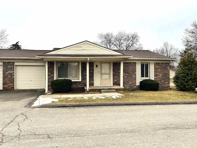 ranch-style house featuring aphalt driveway, brick siding, and an attached garage