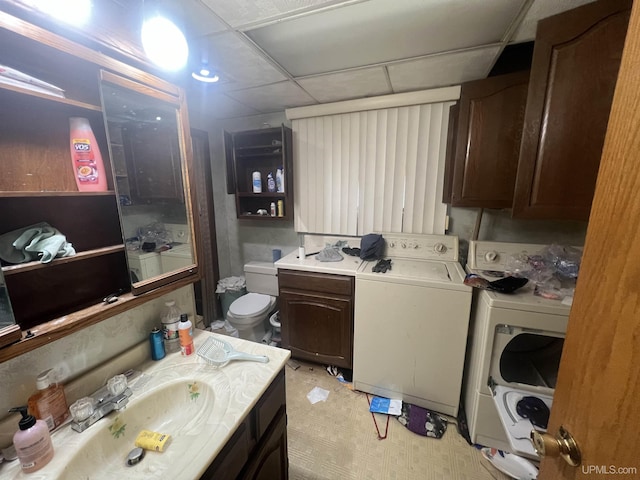 bathroom featuring a paneled ceiling, washing machine and dryer, toilet, and vanity