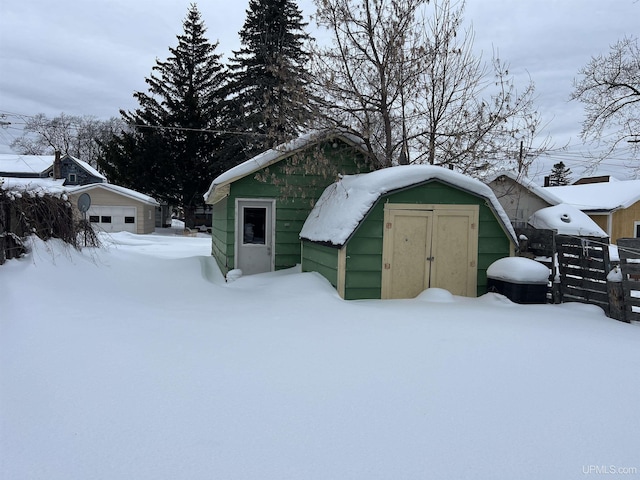 snow covered structure with an outbuilding and a storage unit