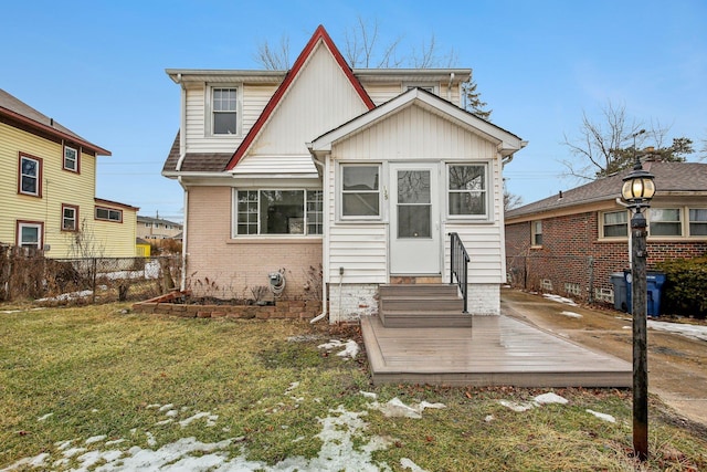 rear view of property with entry steps, brick siding, a yard, and fence