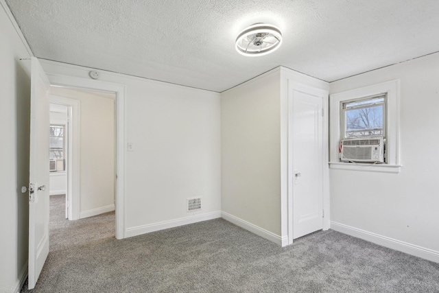 unfurnished bedroom with a textured ceiling, cooling unit, carpet flooring, and visible vents