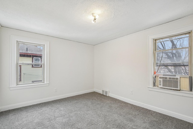 empty room featuring carpet floors, baseboards, visible vents, and a textured ceiling