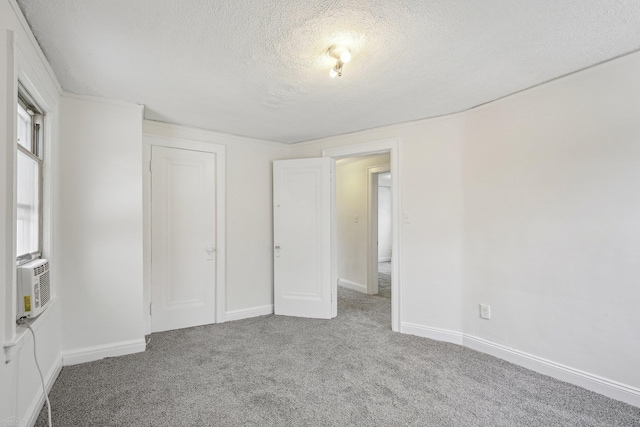 unfurnished bedroom featuring carpet floors, cooling unit, a textured ceiling, and baseboards