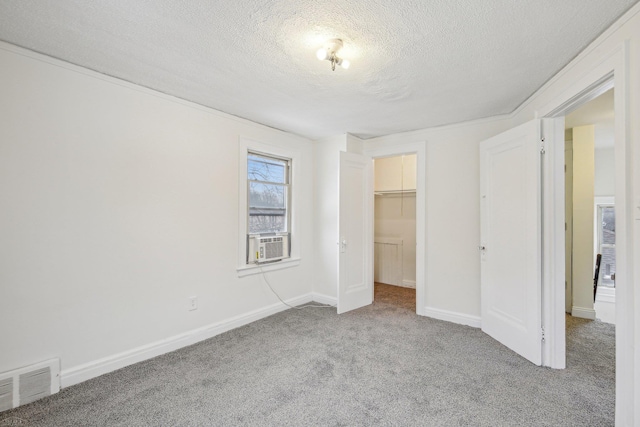 unfurnished bedroom with baseboards, visible vents, carpet, a spacious closet, and a textured ceiling