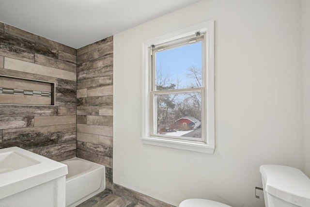 full bath featuring wood finished floors, plenty of natural light, a bathtub, and toilet