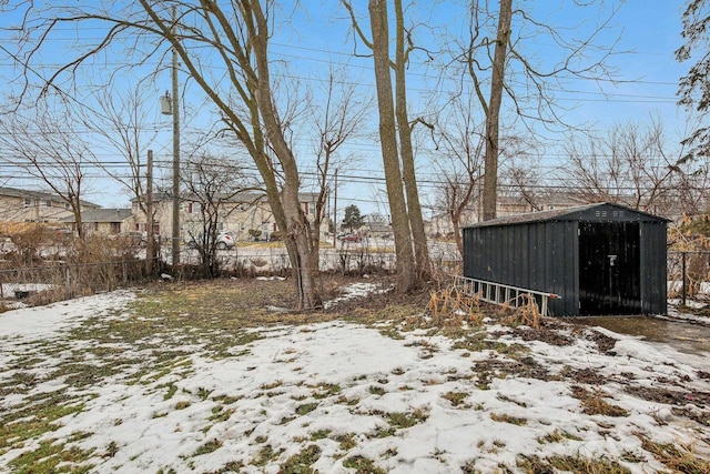 snowy yard featuring an outbuilding, a storage unit, and fence