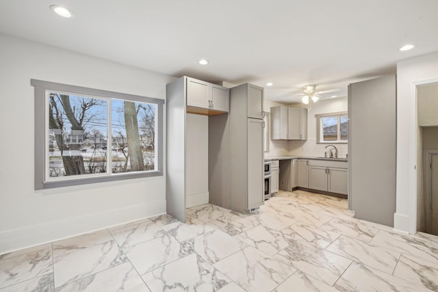 kitchen with recessed lighting, tasteful backsplash, a sink, and gray cabinetry