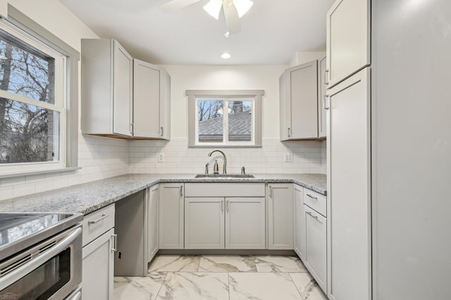 kitchen featuring marble finish floor, light stone counters, backsplash, and a sink