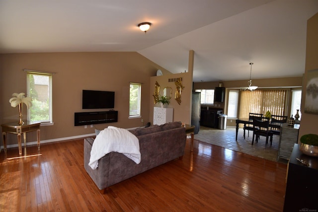 living room featuring lofted ceiling, wood-type flooring, and a healthy amount of sunlight