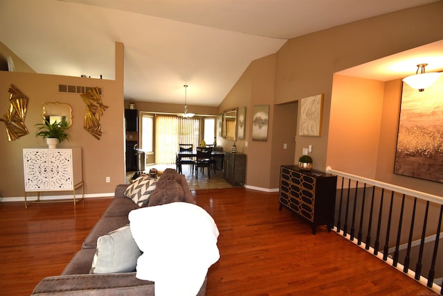 living area featuring vaulted ceiling, wood finished floors, visible vents, and baseboards