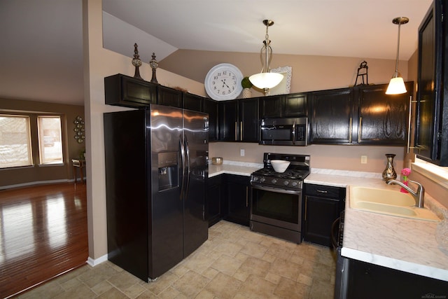 kitchen featuring a sink, vaulted ceiling, light countertops, appliances with stainless steel finishes, and dark cabinetry