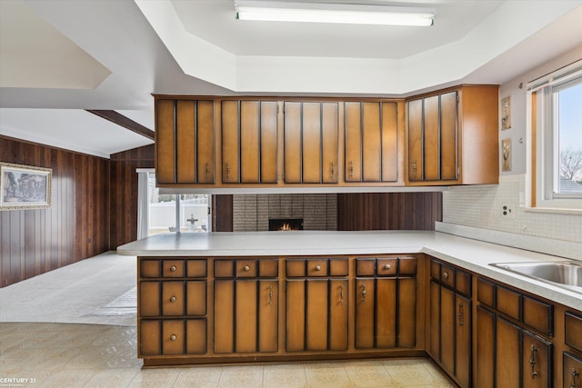 kitchen featuring wooden walls, a peninsula, light countertops, decorative backsplash, and beamed ceiling