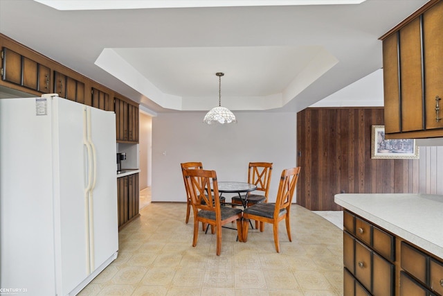 dining space with a raised ceiling and wooden walls