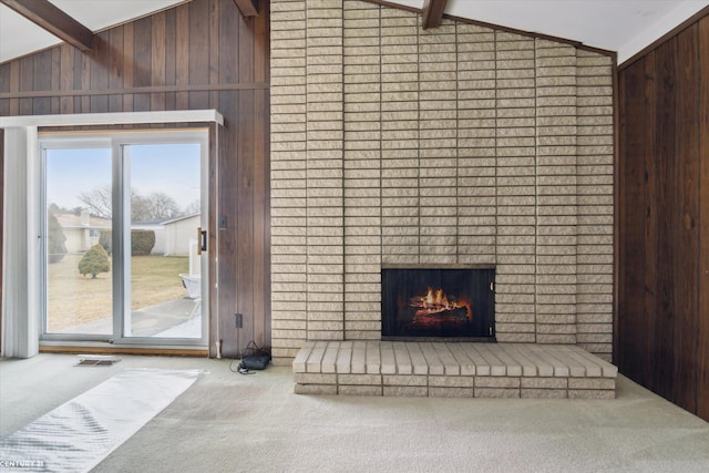 living room featuring lofted ceiling with beams, wood walls, and carpet