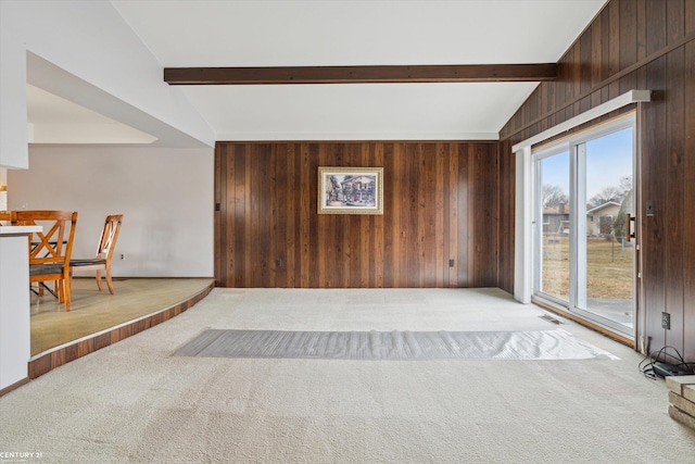 unfurnished living room featuring vaulted ceiling with beams, carpet floors, visible vents, and wooden walls