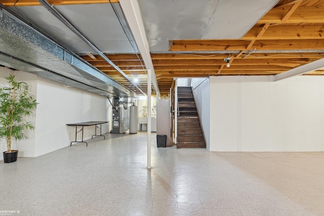 unfinished basement with water heater and stairway