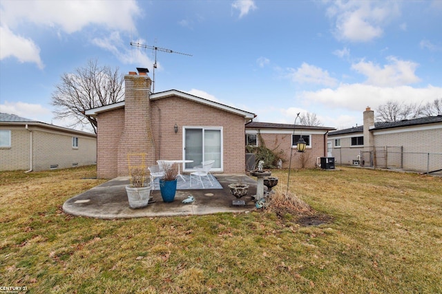 back of house with brick siding, a patio, a chimney, a lawn, and fence