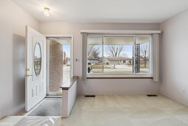 foyer entrance featuring carpet, visible vents, and baseboards