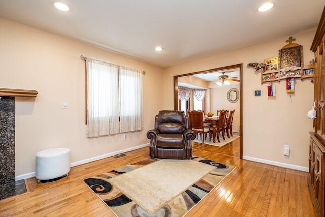 living area with recessed lighting, wood-type flooring, visible vents, and baseboards