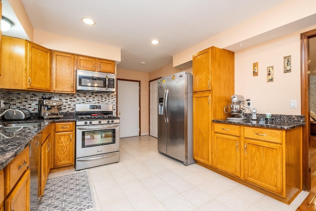 kitchen featuring brown cabinetry, appliances with stainless steel finishes, decorative backsplash, and a sink