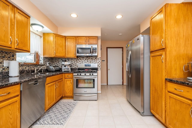 kitchen featuring stainless steel appliances, backsplash, a sink, and brown cabinets