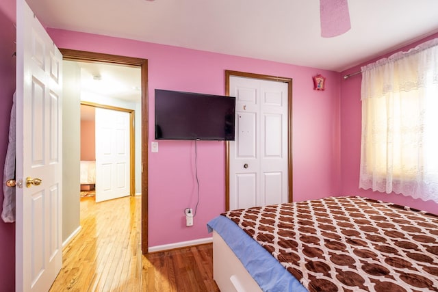 bedroom featuring a closet, ceiling fan, light wood-style flooring, and baseboards