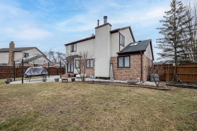 back of property featuring a fenced backyard, a patio, brick siding, and a lawn