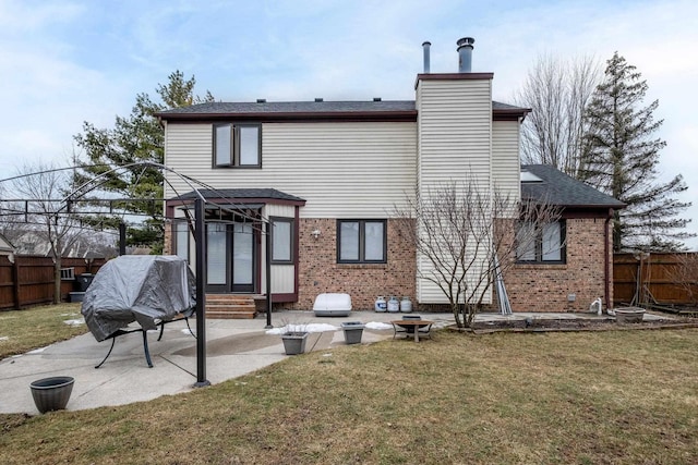 rear view of house with entry steps, brick siding, a lawn, and fence