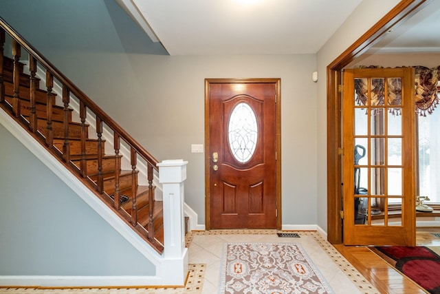 foyer entrance with stairs, baseboards, and light tile patterned floors