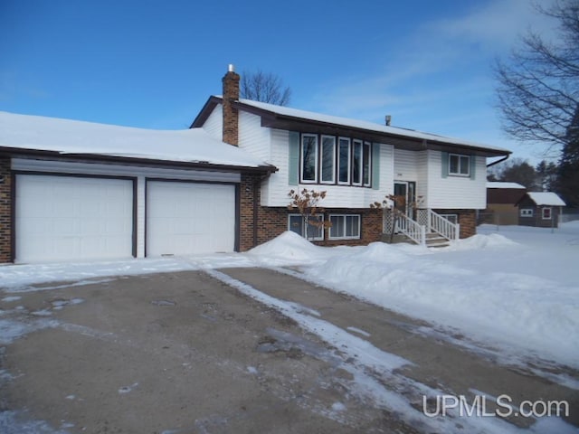 raised ranch with brick siding, a chimney, and an attached garage