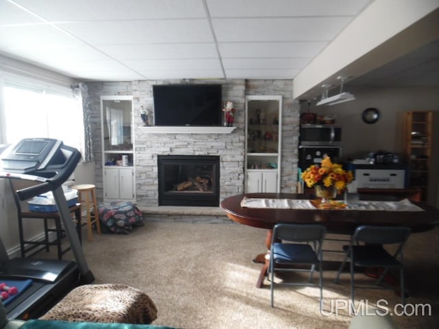 carpeted living area with a paneled ceiling and a stone fireplace