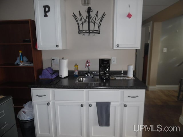 kitchen with dark countertops, white cabinetry, and a sink