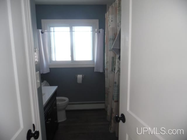 bathroom featuring toilet, vanity, baseboard heating, and wood finished floors