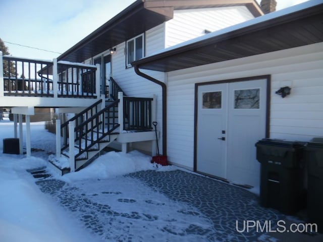 snow covered property entrance with a deck