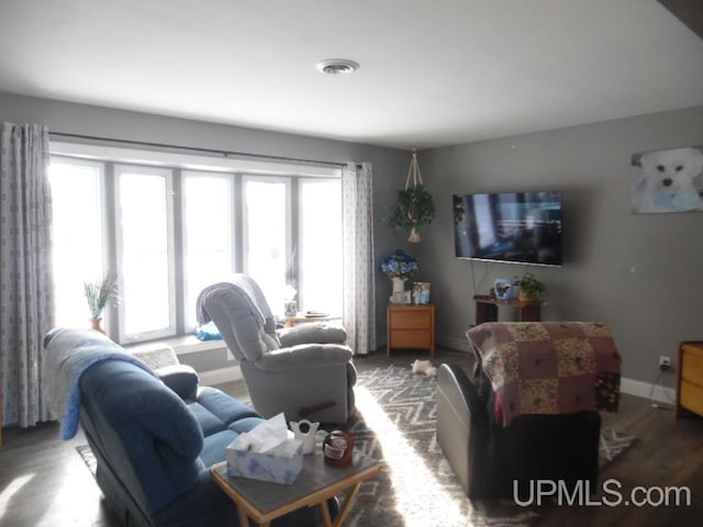 living room with baseboards, visible vents, and wood finished floors