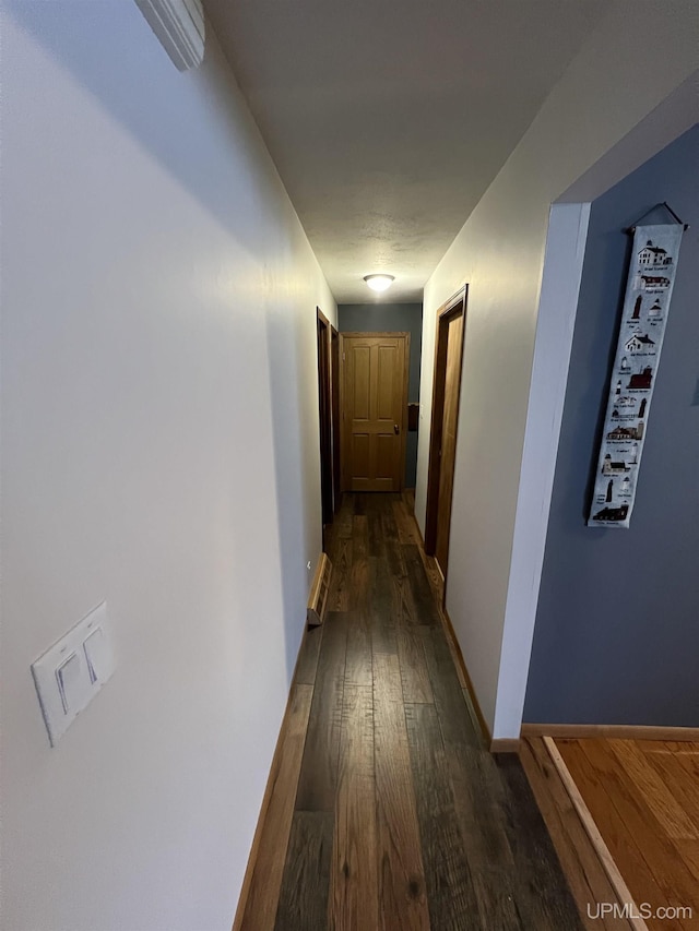 corridor featuring dark wood finished floors and baseboards