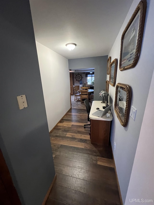 hallway featuring baseboards and dark wood-type flooring