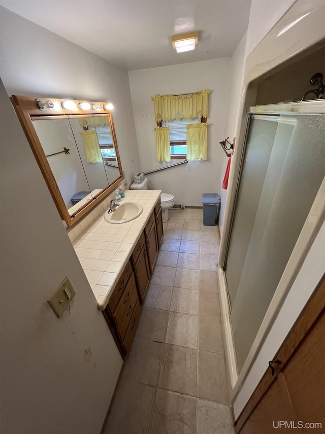 bathroom featuring toilet, a shower stall, and vanity