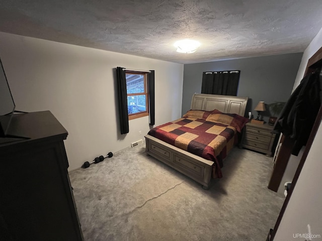 bedroom featuring light carpet, a textured ceiling, and visible vents