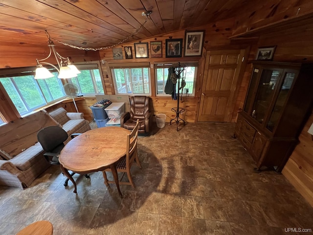 dining space featuring vaulted ceiling, wood walls, wooden ceiling, and an inviting chandelier