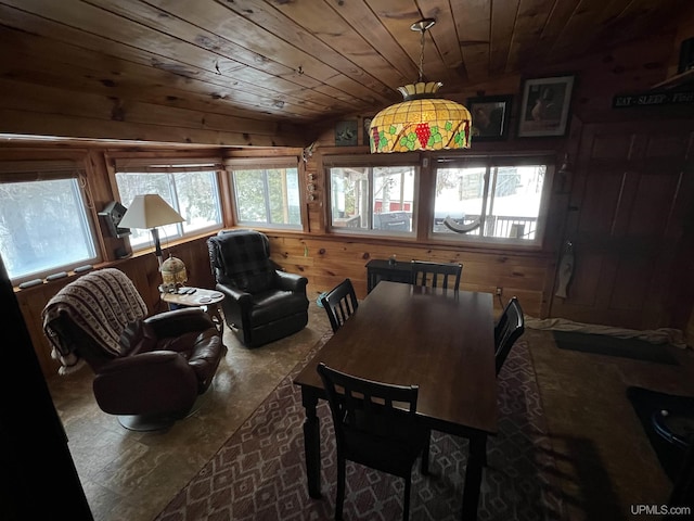 dining space with vaulted ceiling, wood ceiling, and wood walls