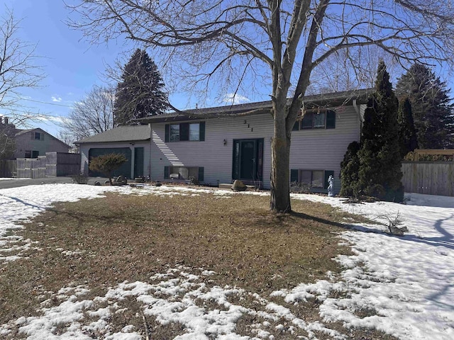 raised ranch featuring a garage and fence