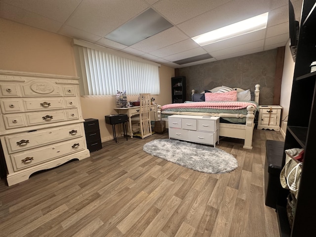 bedroom featuring baseboards, a drop ceiling, and light wood finished floors