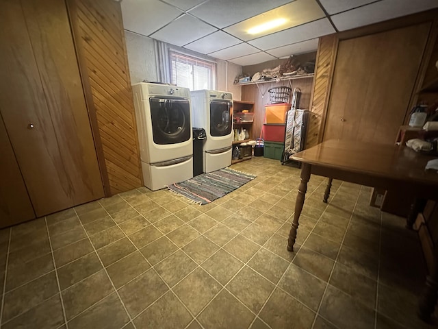 laundry area featuring laundry area, dark tile patterned floors, washer and dryer, and wood walls