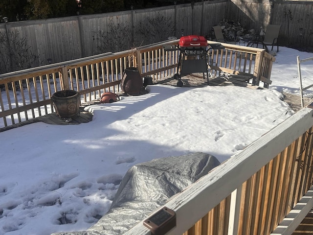 snow covered deck with grilling area and fence